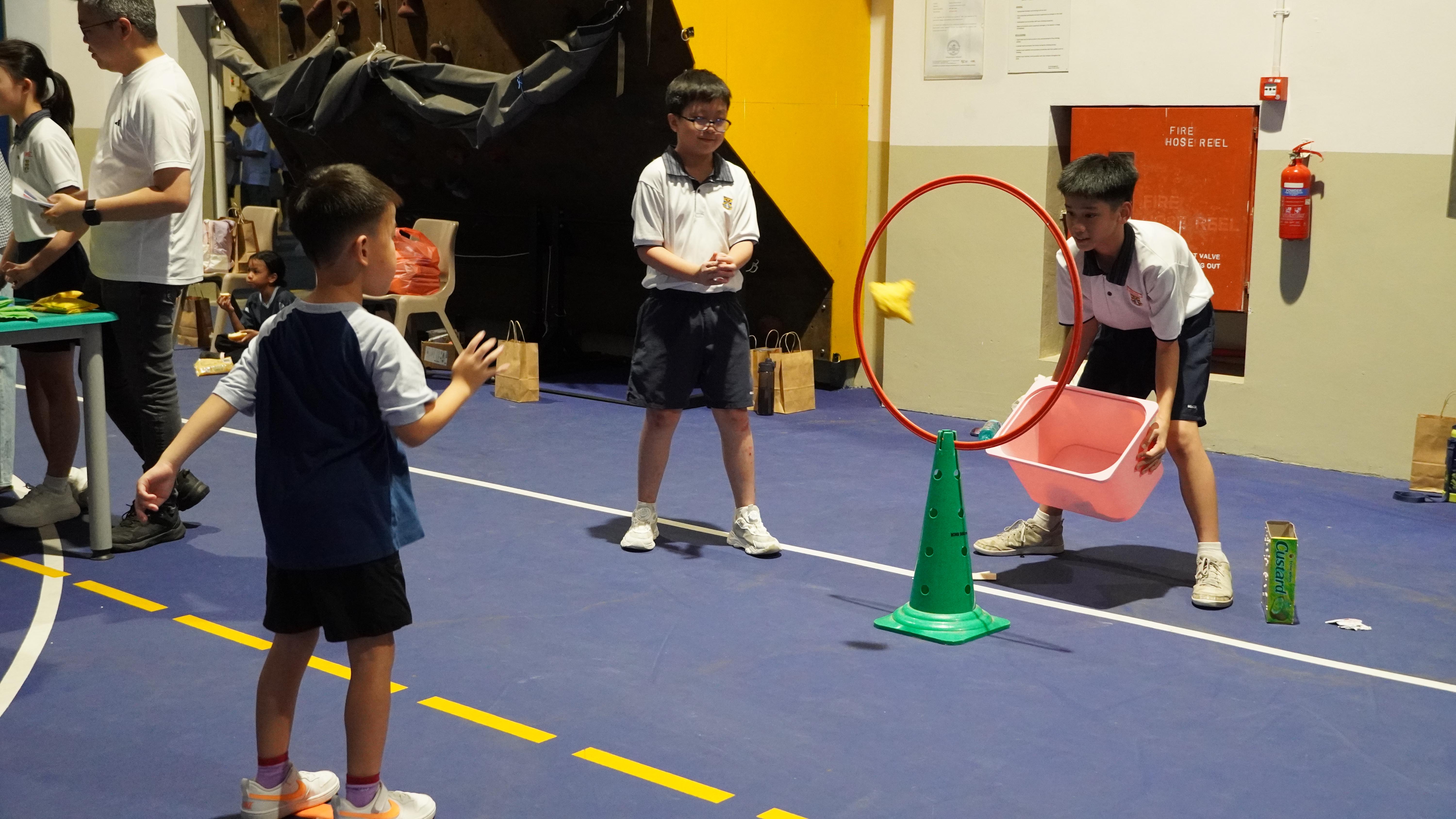 Ready, aim, toss! A little focus, a steady throw, and plenty of fun as our student takes on the hoop challenge!